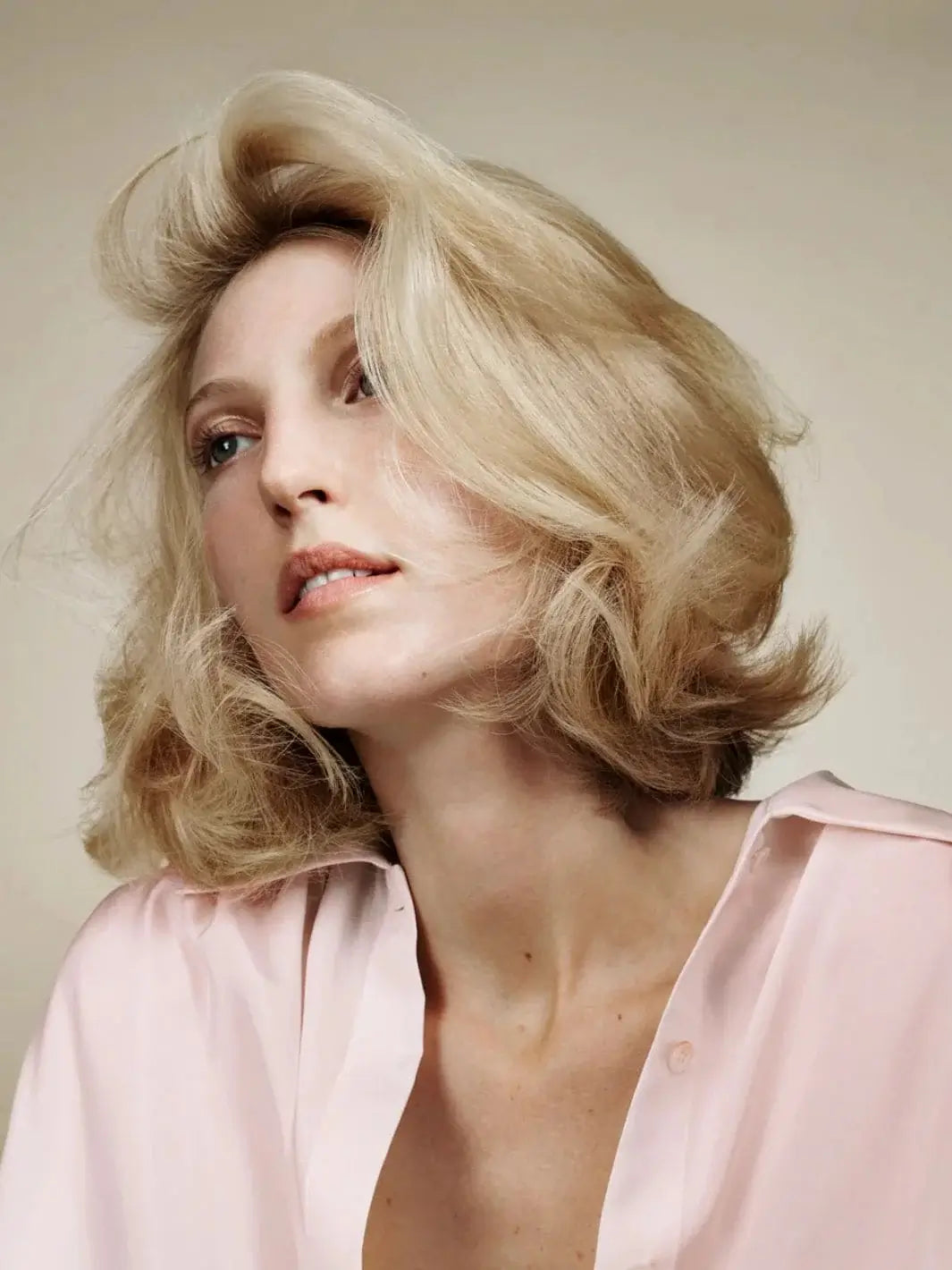 A blonde model with a high-volume, windswept blowout look showcasing the results of Hair by Sam McKnight Cool Girl Volume Shampoo | Twentyseven Toronto