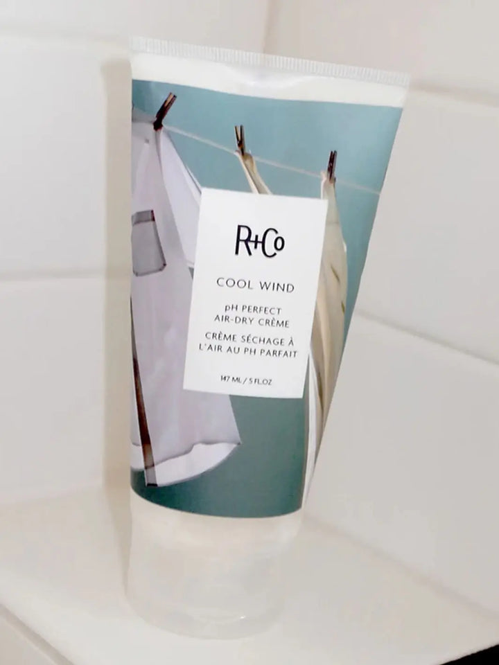 Close up of R+Co 'COOL WIND pH Perfect Air-Dry Creme' packaging on a white bathroom background, 147ml | Twentyseven Toronto