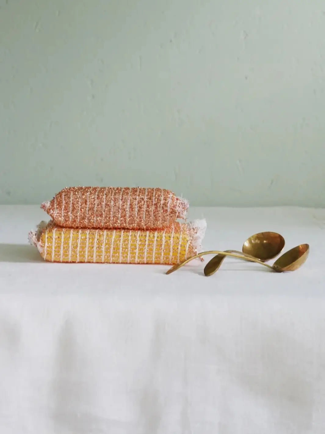 2 copper sponges from Burstenhaus Redecker and brass spoons on a table | Twentyseven Toronto