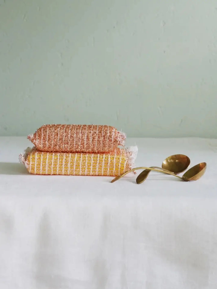 2 copper sponges from Burstenhaus Redecker and brass spoons on a table | Twentyseven Toronto