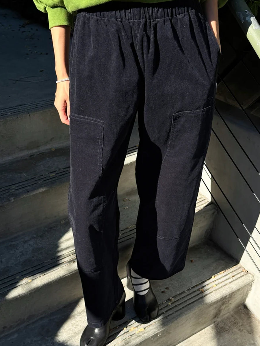Model wearing Le Bon Shoppe Corduroy Gardener's Pants in navy with a green sweatshirt and black heels, showing the relaxed fit, elastic waist and utility pockets | Twentyseven Toronto