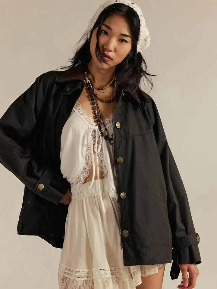 A medium studio shot shows a model posing in the Free People Cori Waxed Jacket in Olive, highlighting its front zipper and large metal buttons | Twentyseven Toronto