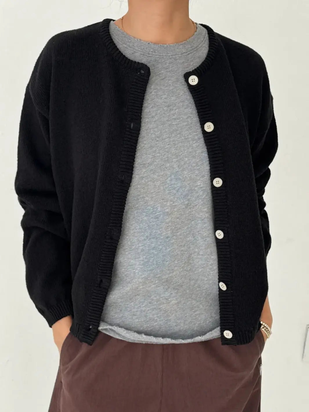 A close-up shot shows a person wearing the Le Bon Shoppe Cotton Leila Cardigan - Black unbuttoned over a grey t-shirt | Twentyseven Toronto