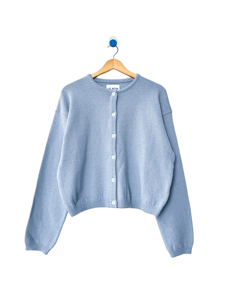 Light blue 'Cotton Leila Cardigan' in 'Cornflower' from Le Bon Shoppe on a wooden hanger on transparent background | Twentyseven Toronto