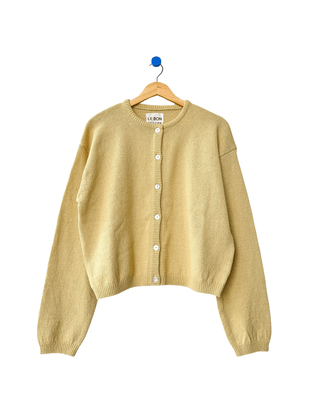 Light yellow 'Cotton Leila Cardigan' in 'Custard' on a wooden hanger on transparent background | Twentyseven Toronto