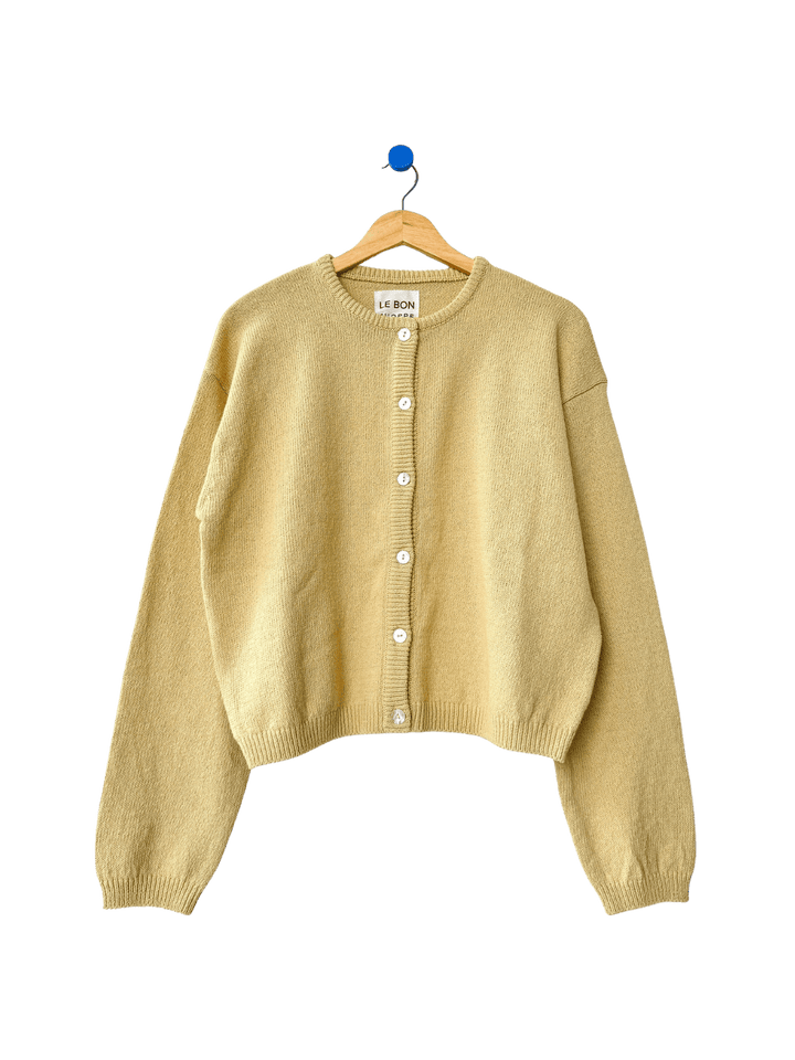 Light yellow 'Cotton Leila Cardigan' in 'Custard' on a wooden hanger on transparent background | Twentyseven Toronto