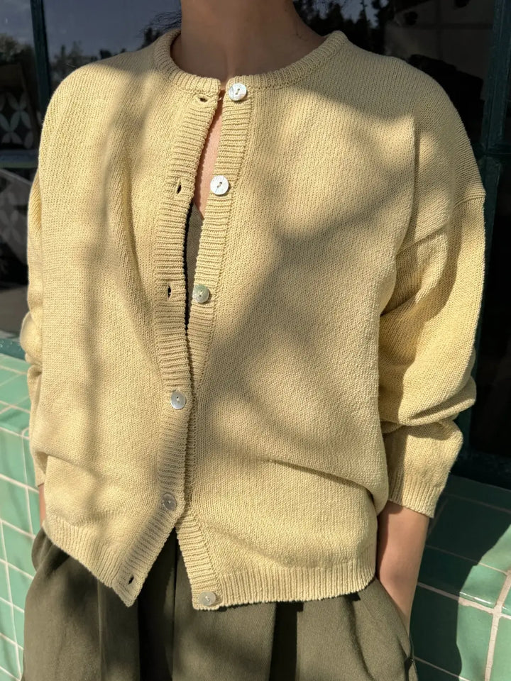 Person wearing a light yellow 'Cotton Leila Cardigan' in 'Custard' from Le Bon Shoppe against a tiled background | Twentyseven Toronto