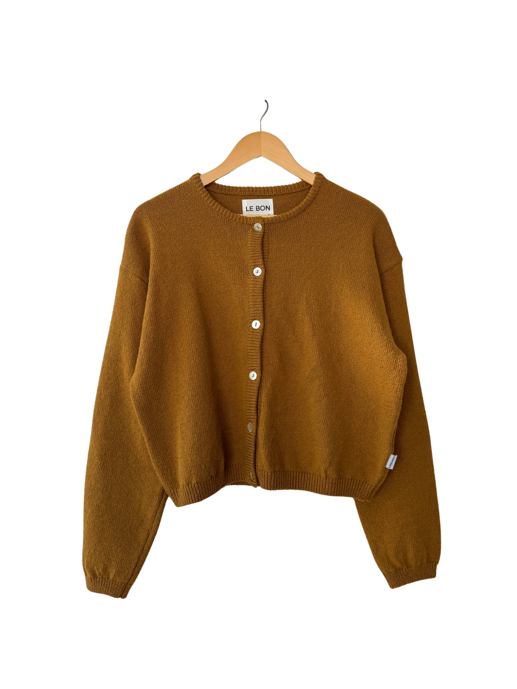 Mustard yellow 'Cotton Leila Cardigan' in 'Dijon' from Le Bon Shoppe on a wooden hanger on transparent background | Twentyseven Toronto