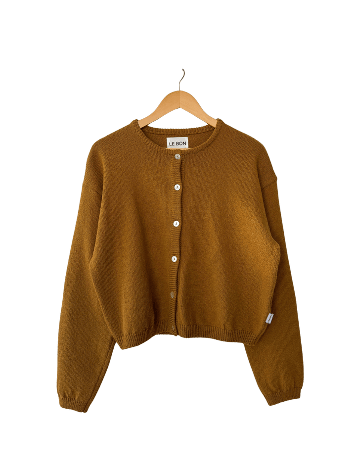 Mustard yellow 'Cotton Leila Cardigan' in 'Dijon' from Le Bon Shoppe on a wooden hanger on transparent background | Twentyseven Toronto