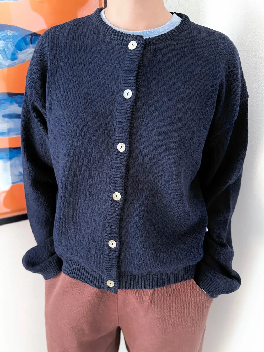 Person wearing a navy blue 'Cotton Leila Cardigan' in 'Navy' with brown shorts from Le Bon Shoppe in an indoor setting | Twentyseven Toronto