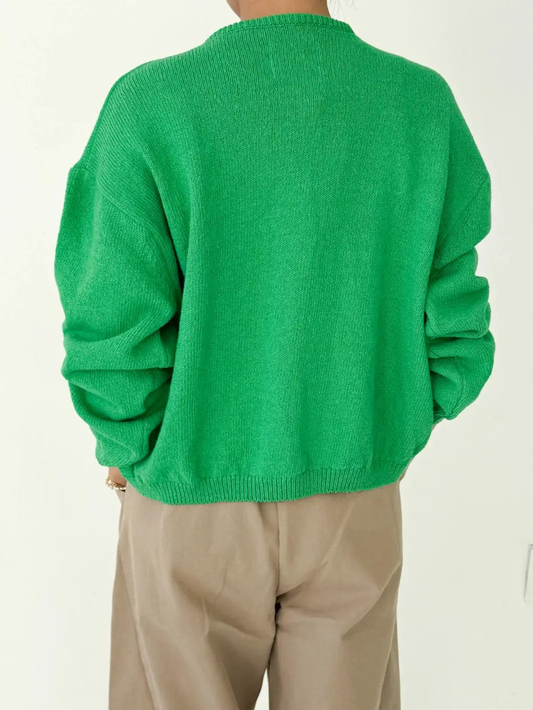 Back view of person wearing a green 'Cotton Leila Cardigan' in 'Spring Green' with beige pants from Le Bon Shoppe on a white background | Twentyseven Toronto