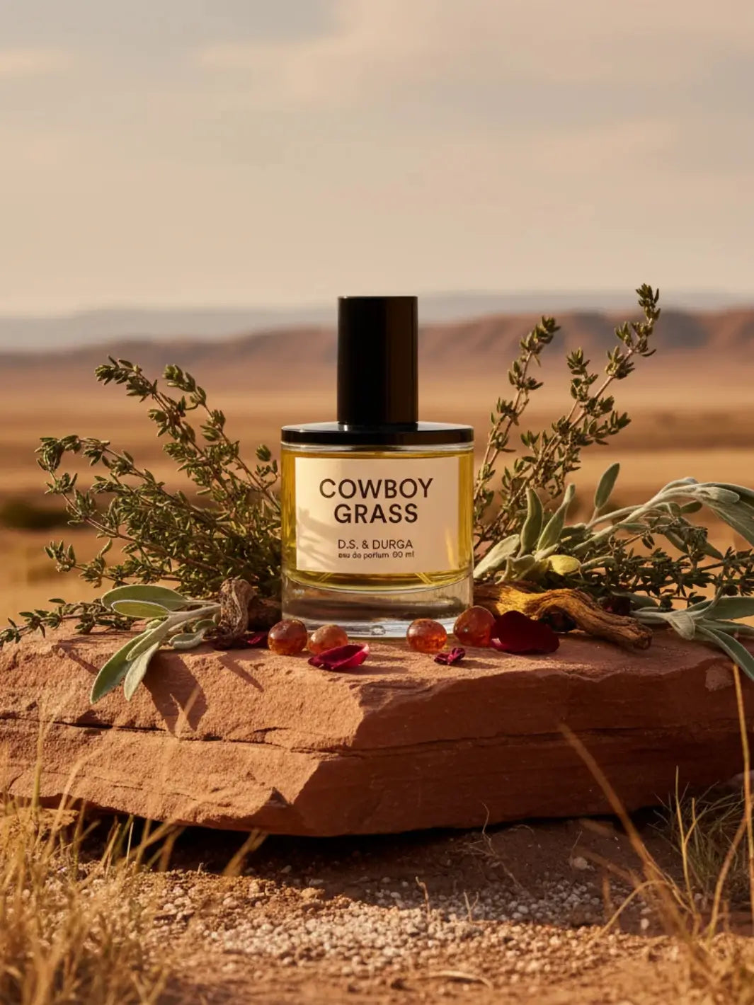 50ml perfume bottle labeled 'Cowboy Grass' on a rock with desert landscape in the background | Twentyseven Toronto