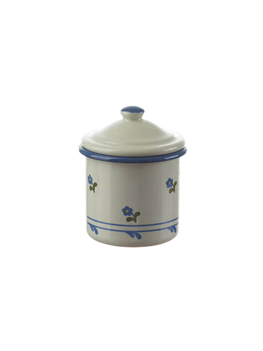 A small, cylindrical cream enamel canister featuring a blue rim, a matching lid with a blue-tipped knob, and a delicate blue floral pattern on the sides, showcasing the Munder Email Cream/Blue Floral Sugar Bowl | Twentyseven Toronto