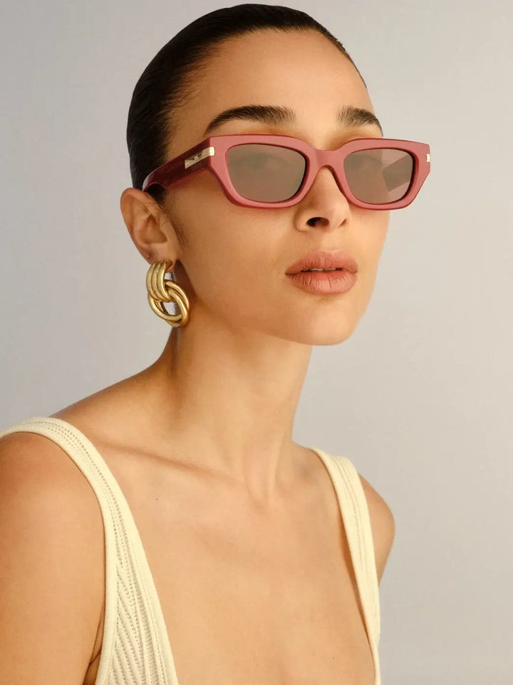 A woman wearing the classic rectangular shape of the Le Specs Cubito + | Burgundy sunglasses paired with gold hoop earrings | Twentyseven Toronto