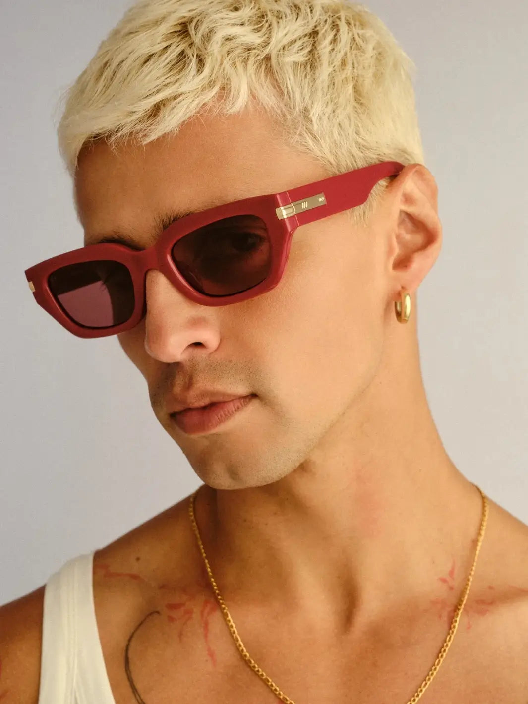 A man with blonde hair looking down while wearing the Le Specs Cubito + in Burgundy sunglasses | Twentyseven Toronto