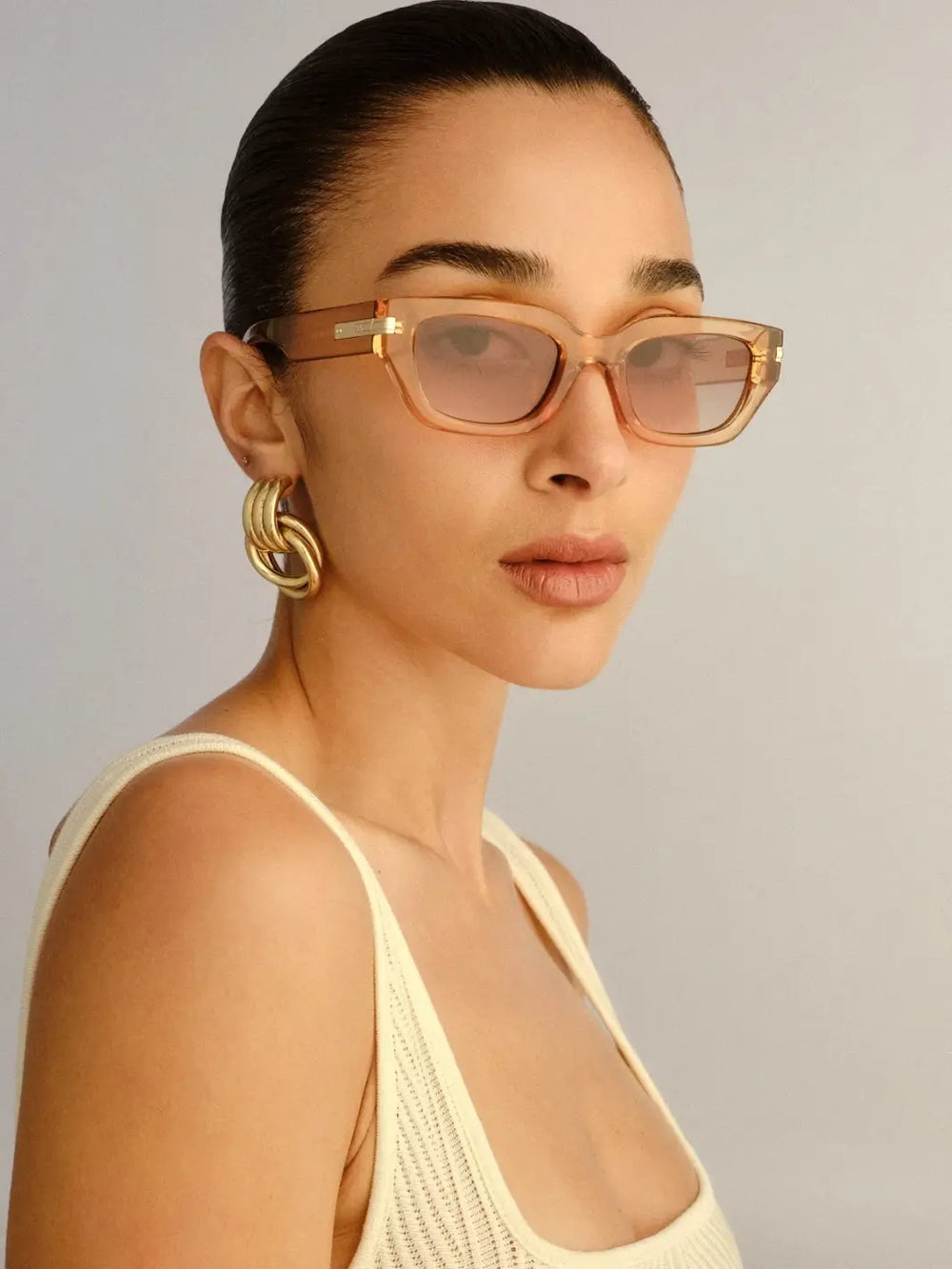 A woman wearing translucent, honey-colored Le Specs Cubito + | Sand sunglasses | Twentyseven Toronto