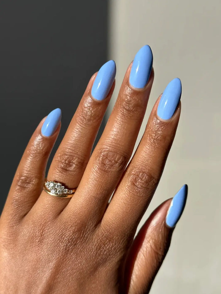 A hand with a deep skin tone and long, oval nails coated in light blue Death Valley Nails Curiosity Cloud Nail Polish | Twentyseven Toronto