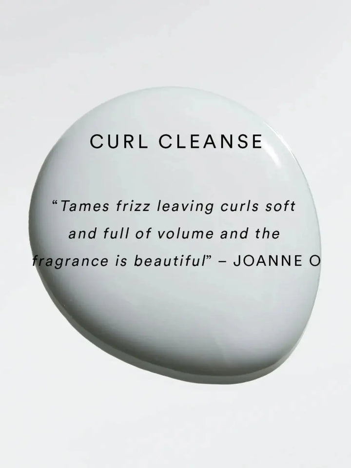 A white droplet of product serves as the background for a positive user review praising the frizz-taming abilities and beautiful fragrance of Hair by Sam McKnight Curl Cleanse Cleansing Conditioner | Twentyseven Toronto
