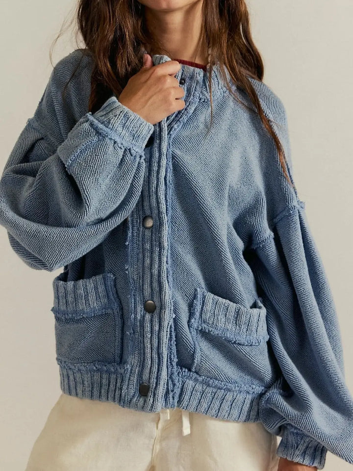 A close-up front view highlights the ribbed knit trim, large front pockets, and snap button closure of the slouchy Free People Cute In This Cardi - Dusty Blue | Twentyseven Toronto