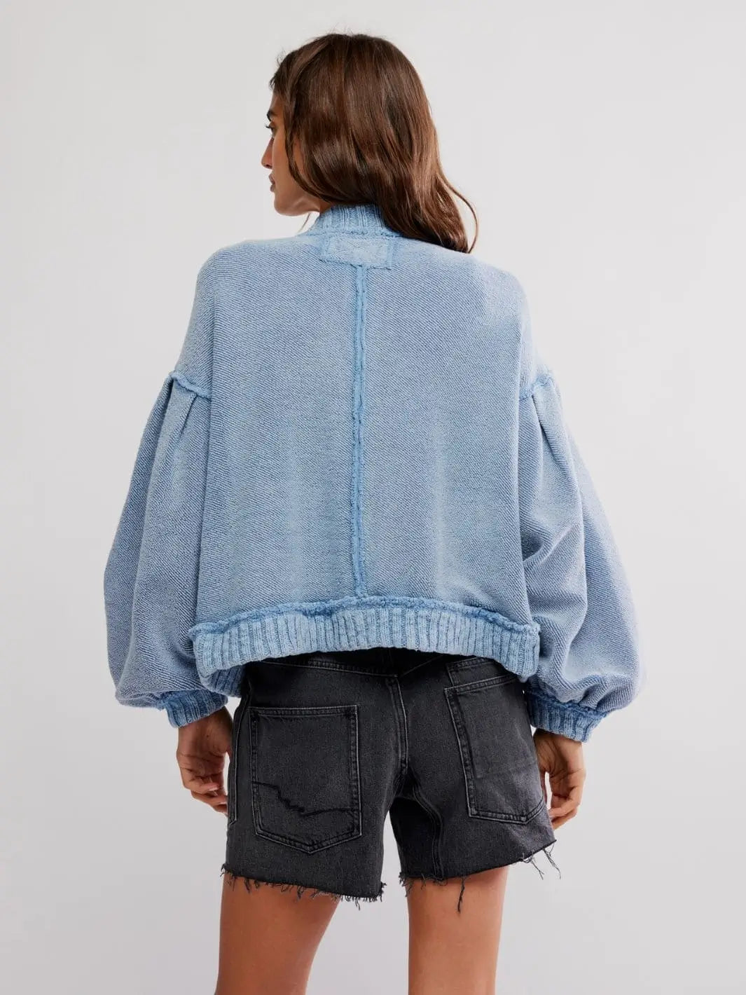 A full rear view shows the casual fit and center back seam of the textured Free People Cute In This Cardi - Dusty Blue paired with grey shorts | Twentyseven Toronto