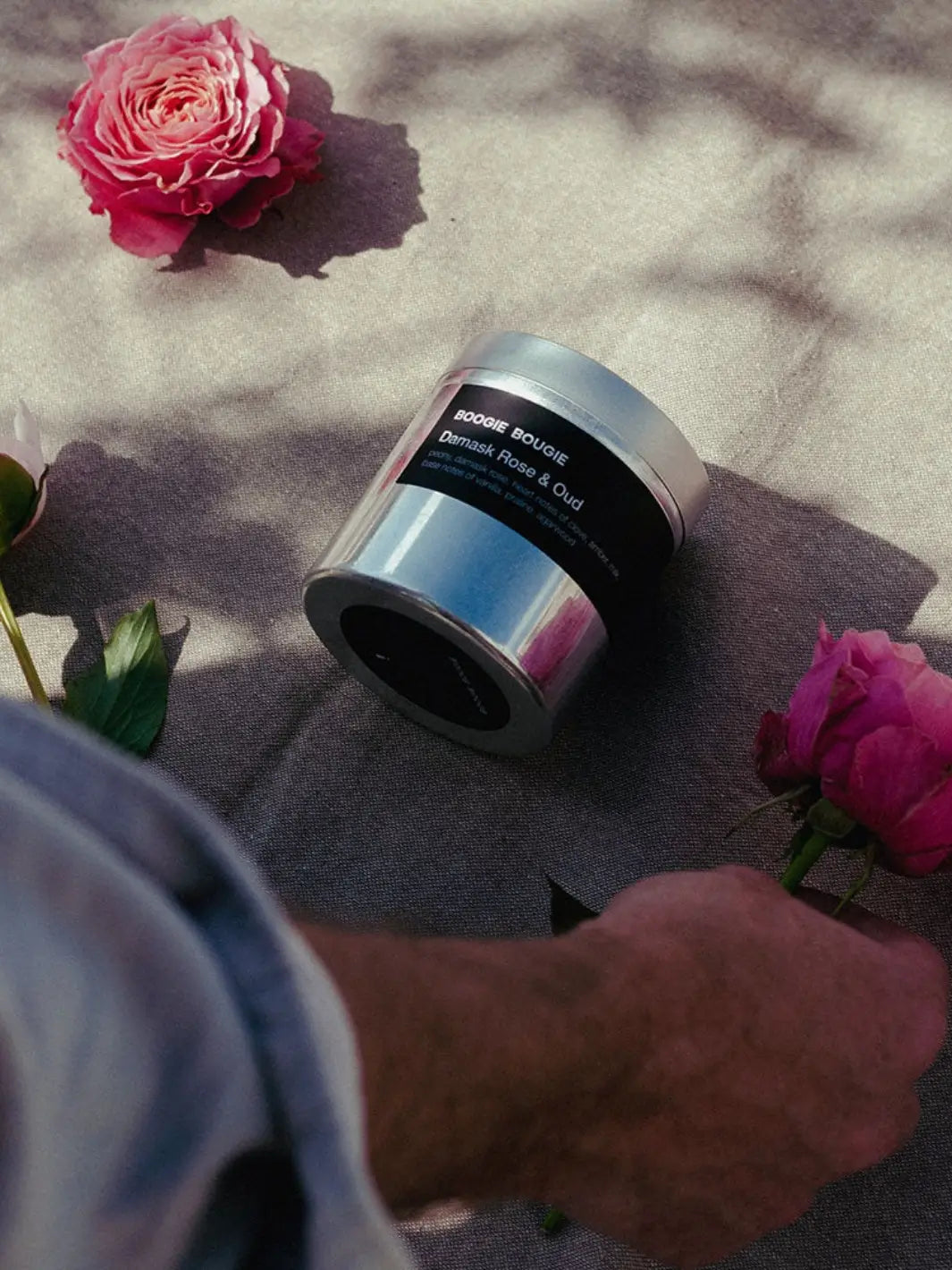 Silver Damask Rose and Oud candle container with 'Boogie Bougie' black label on a textured surface with pink flowers | Twentyseven Toronto