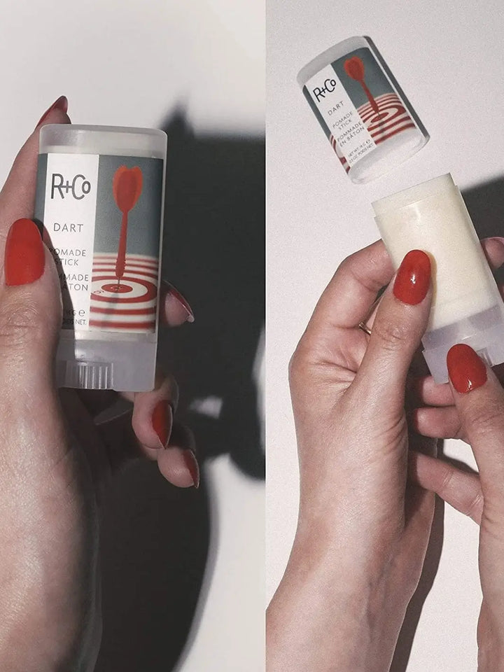 A side-by-side product demonstration shows a capped R+Co DART Pomade Stick on the left, and an open, twist-up version being held on the right against a plain white background | Twentyseven Toronto