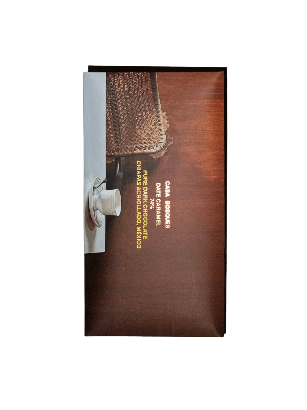 Wrapper of Date Caramel 74% Chocolate Bar from Casa Bosques featuring gold typography over an warm-toned image of a woven chair and a white espresso cup | Twentyseven Toronto