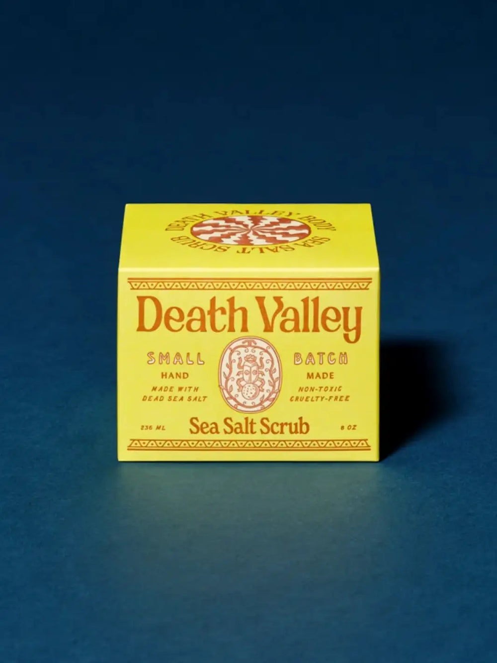 Bright yellow product box for Death Valley Nails Dead Sea Salt Scrub - Lemon + Sage + Peppermint + Earth set against a deep blue background | Twentyseven Toronto