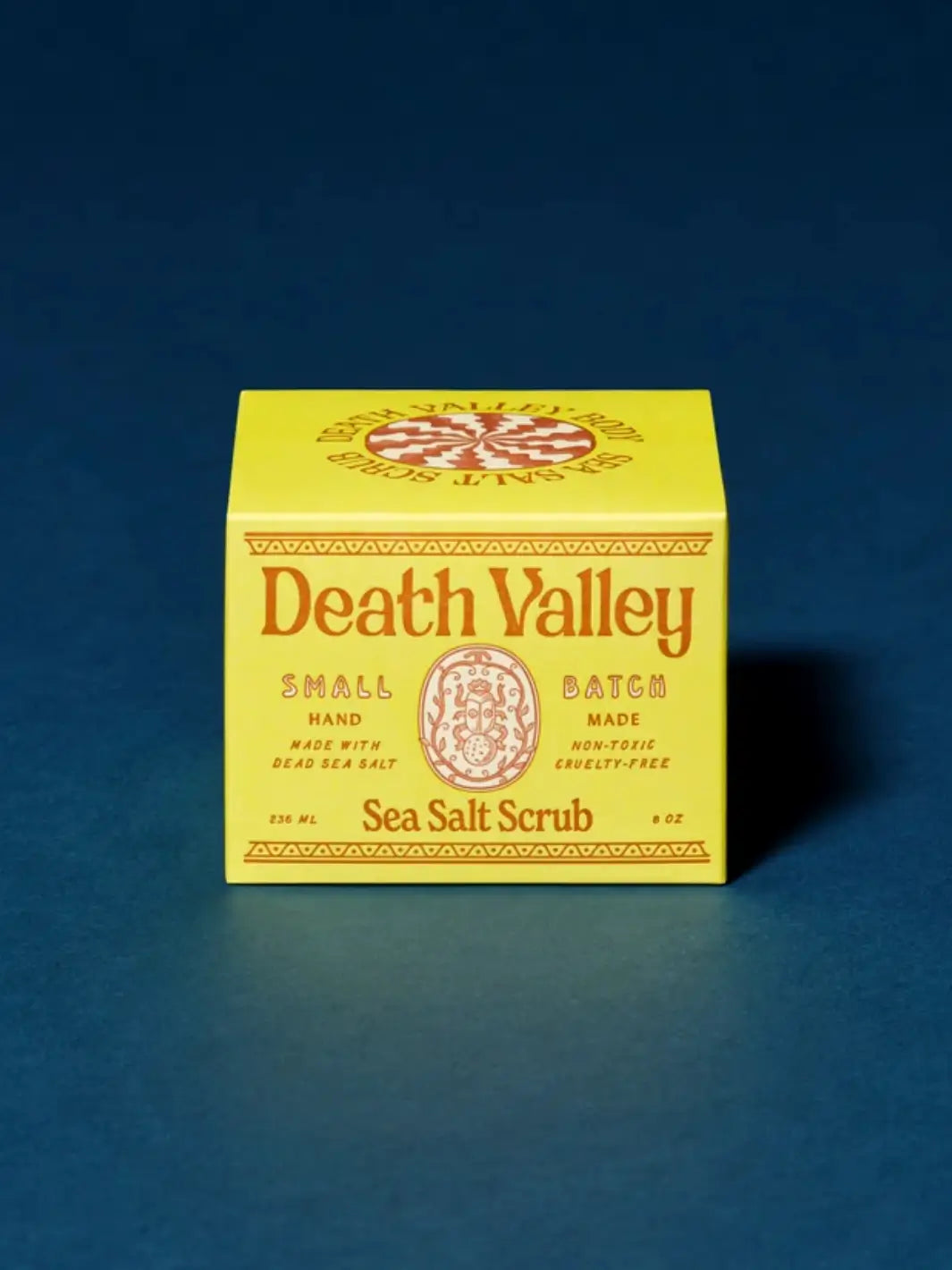 Bright yellow product box for Death Valley Nails Dead Sea Salt Scrub - Lemon + Sage + Peppermint + Earth set against a deep blue background | Twentyseven Toronto