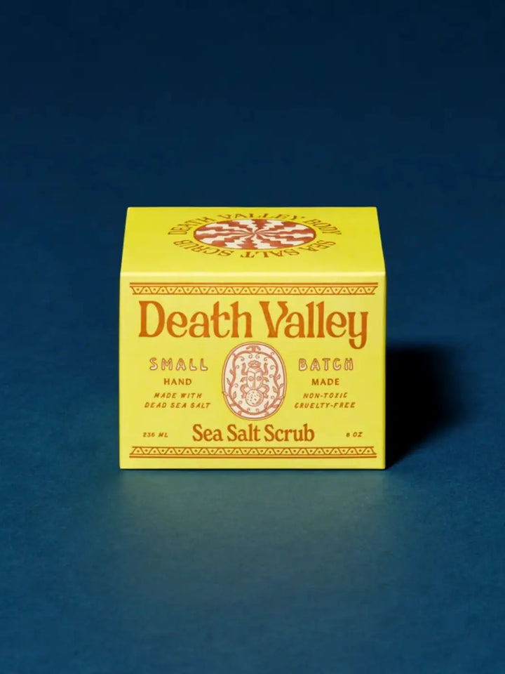 Bright yellow product box for Death Valley Nails Dead Sea Salt Scrub - Lemon + Sage + Peppermint + Earth set against a deep blue background | Twentyseven Toronto