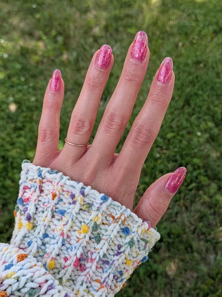 Pink multichrome glitter manicure on almond-shaped nails photographed outdoors in natural light | Twentyseven Toronto
