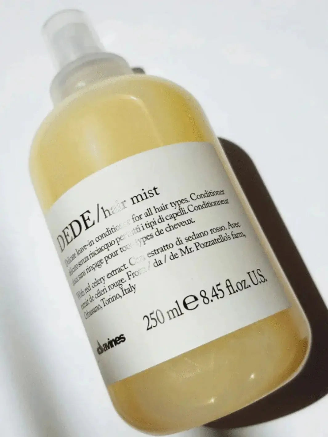A spray bottle of Davines DEDE Leave-in Conditioner liquid sits at an angle against a bright white background | Twentyseven Toronto