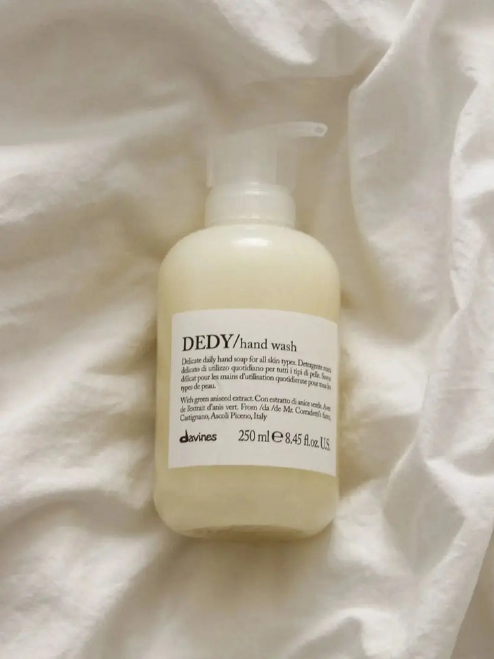 A plastic pump bottle of Davines DEDY Hand Wash is against a background of soft, rumpled white fabric | Twentyseven Toronto
