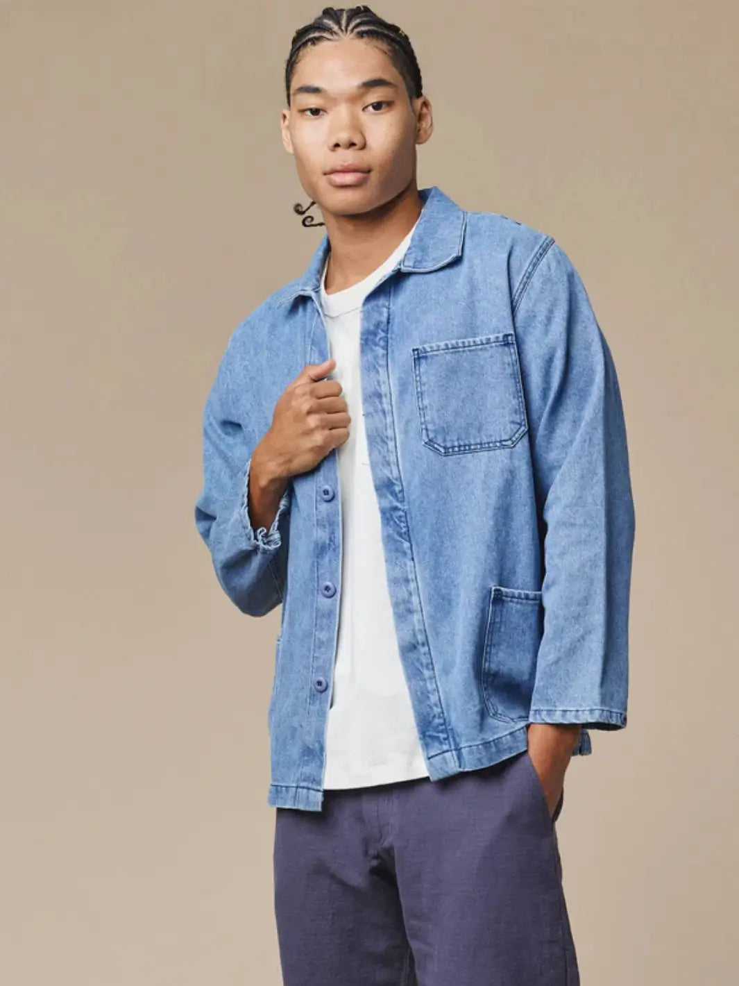 A model poses from the waist up wearing the open Jungmaven Denim Olympic Jacket in Light over a plain white t-shirt and purple shorts, showcasing the front patch pockets | Twentyseven Toronto