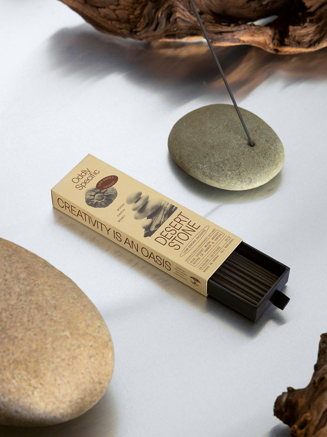 Oddly Specific Desert Stone Low Smoke Incense with an open black tray of incense sticks, styled beside a grey stone incense holder, natural rocks and driftwood | Twentyseven Toronto
