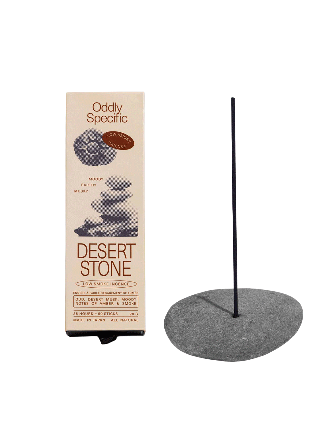 Oddly Specific Desert Stone Low Smoke Incense in beige packaging with stacked stone illustrations, displayed beside a dark incense stick in a grey stone holder | Twentyseven Toronto