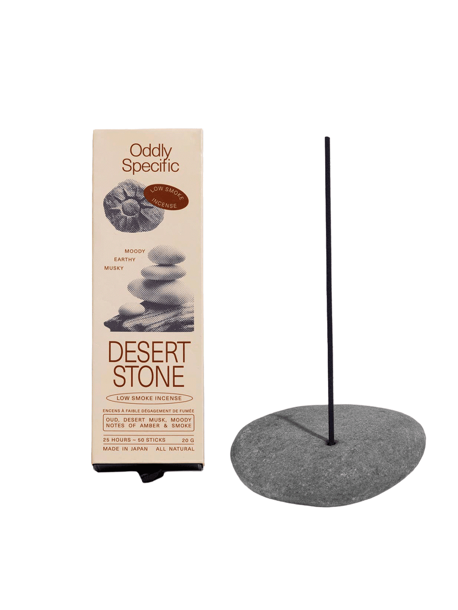 Oddly Specific Desert Stone Low Smoke Incense in beige packaging with stacked stone illustrations, displayed beside a dark incense stick in a grey stone holder | Twentyseven Toronto