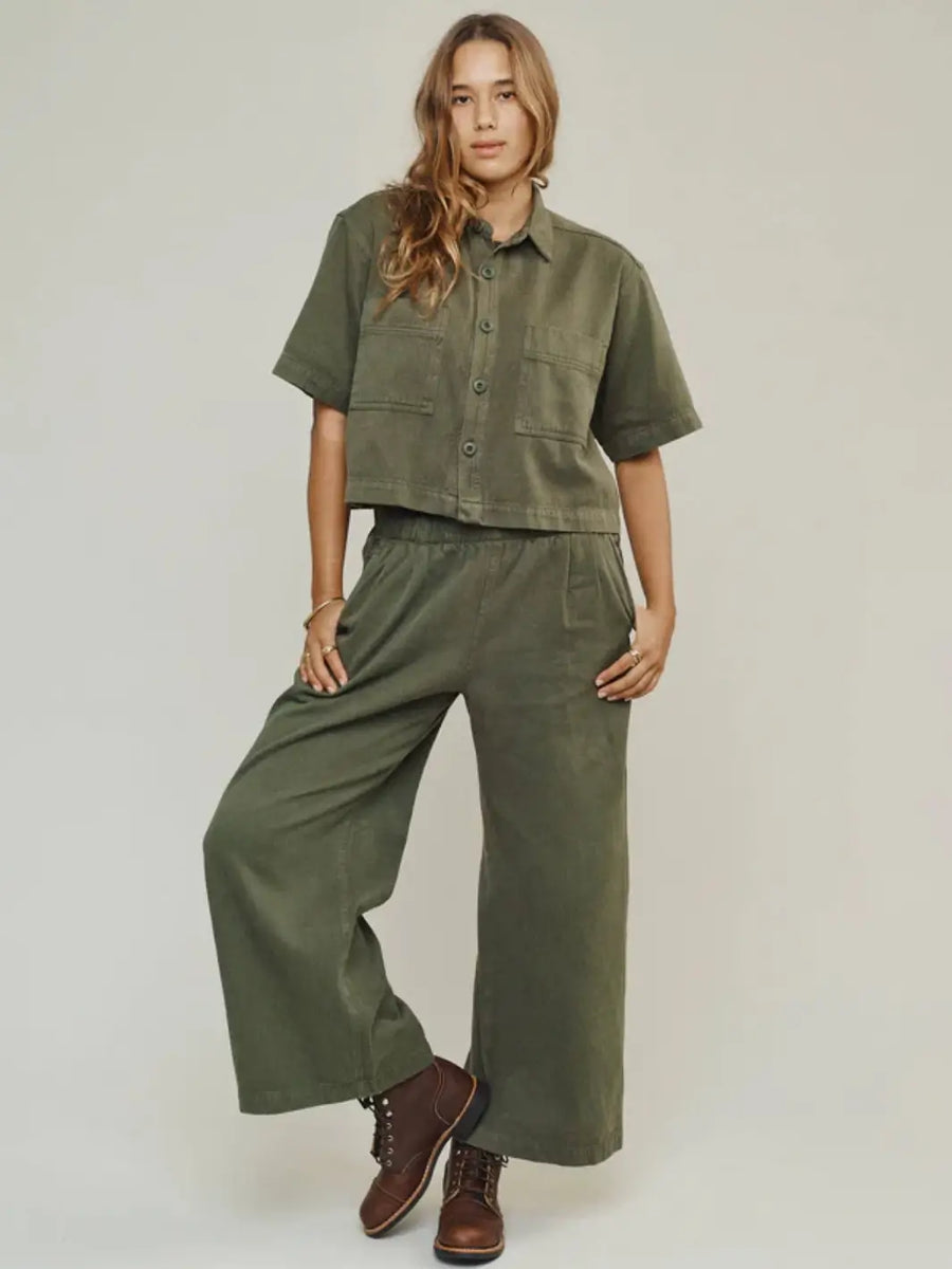 A model poses from the front wearing a matching olive green utility shirt paired with the loose-fitting Jungmaven Disco Twill Pant - Olive Green and brown leather boots | Twentyseven Toronto