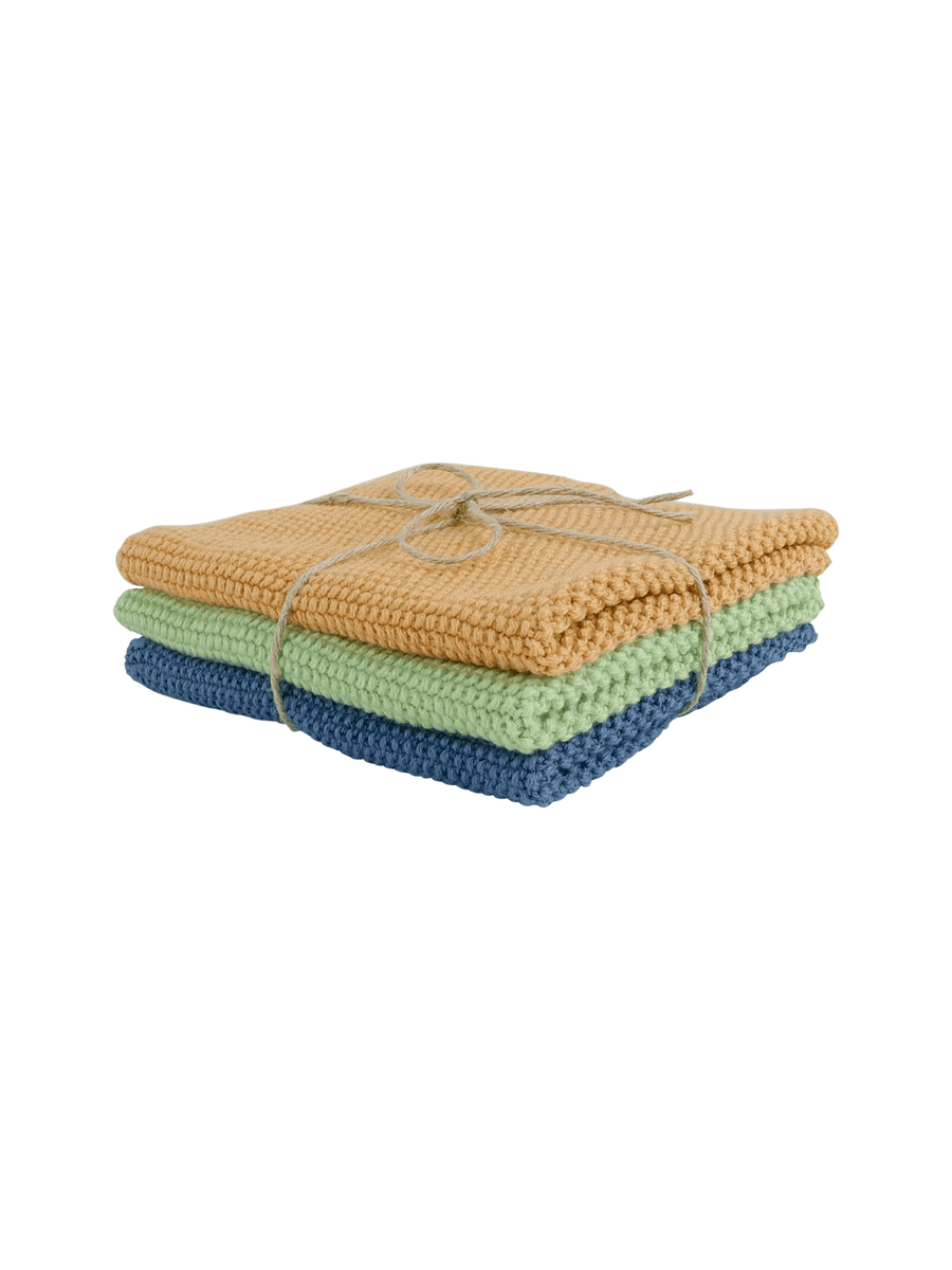 Stack of folded knitted dishcloths in orange, green, and blue tied with twine from Burstenhaus Redecker on a transparent background | Twentyseven Toronto