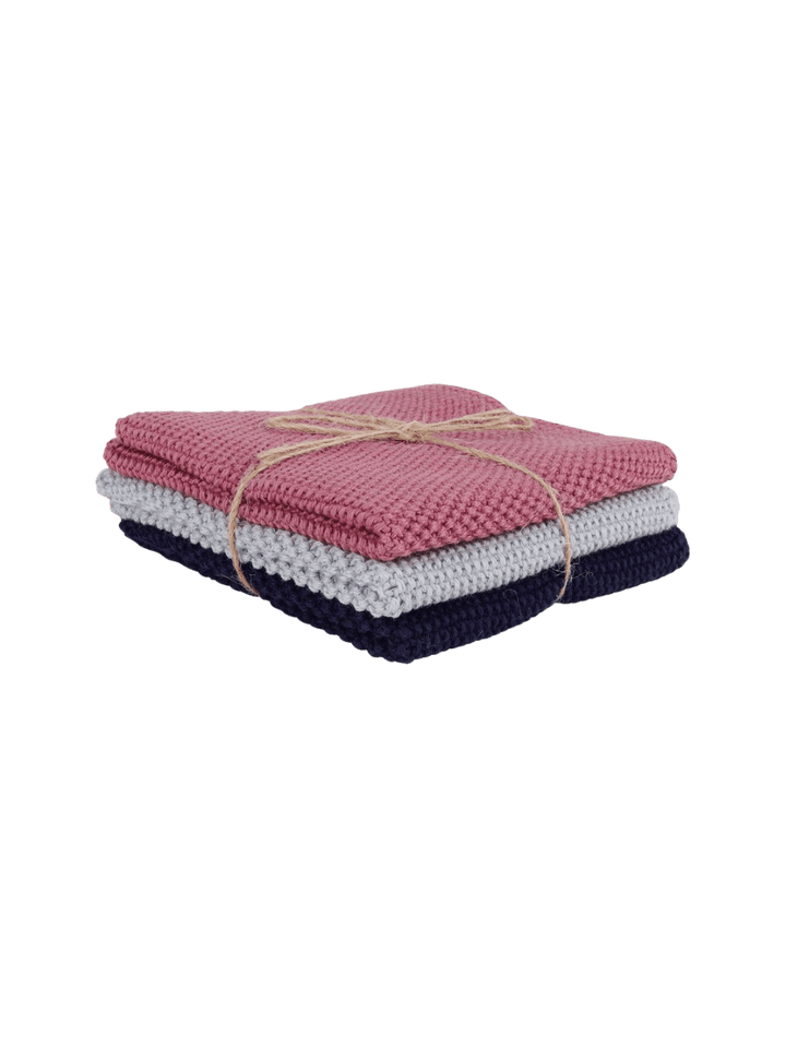 Stack of folded knitted dishcloths in pink, white, and navy tied with twine from Burstenhaus Redecker on a transparent background | Twentyseven Toronto