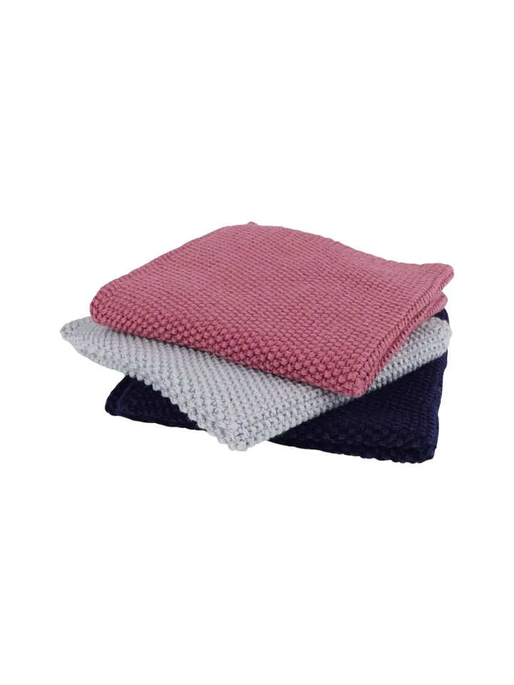 Stack of folded knitted dishcloths in pink, white, and navy tied with twine from Burstenhaus Redecker on a white background | Twentyseven Toronto