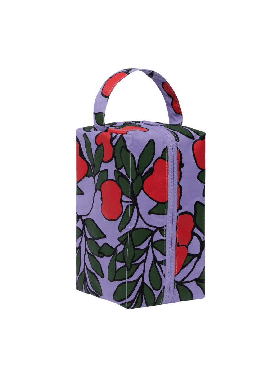 A rectangular BAGGU Dopp Kit in Apple Tree features a purple background with a red apple and green leaf pattern and a top carry handle | Twentyseven Toronto
