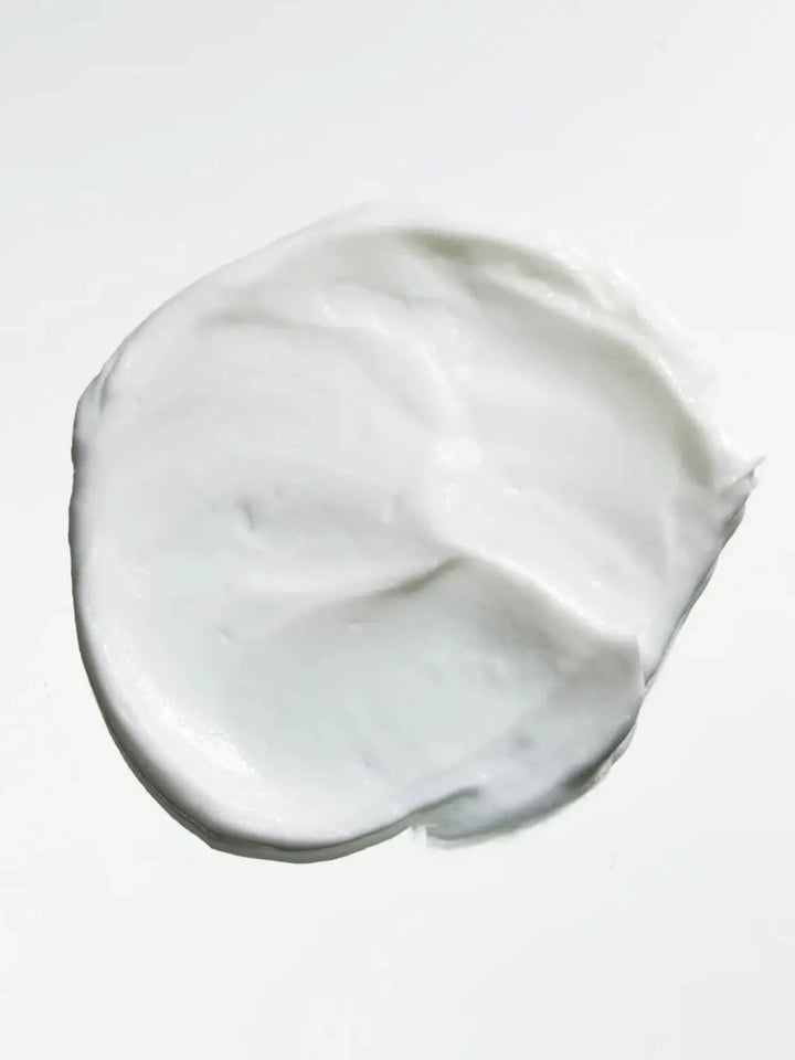 A smooth, circular dollop of white Hair by Sam McKnight Dressed to Kill Define and Defrizz Creme smeared against a clean white background | Twentyseven Toronto