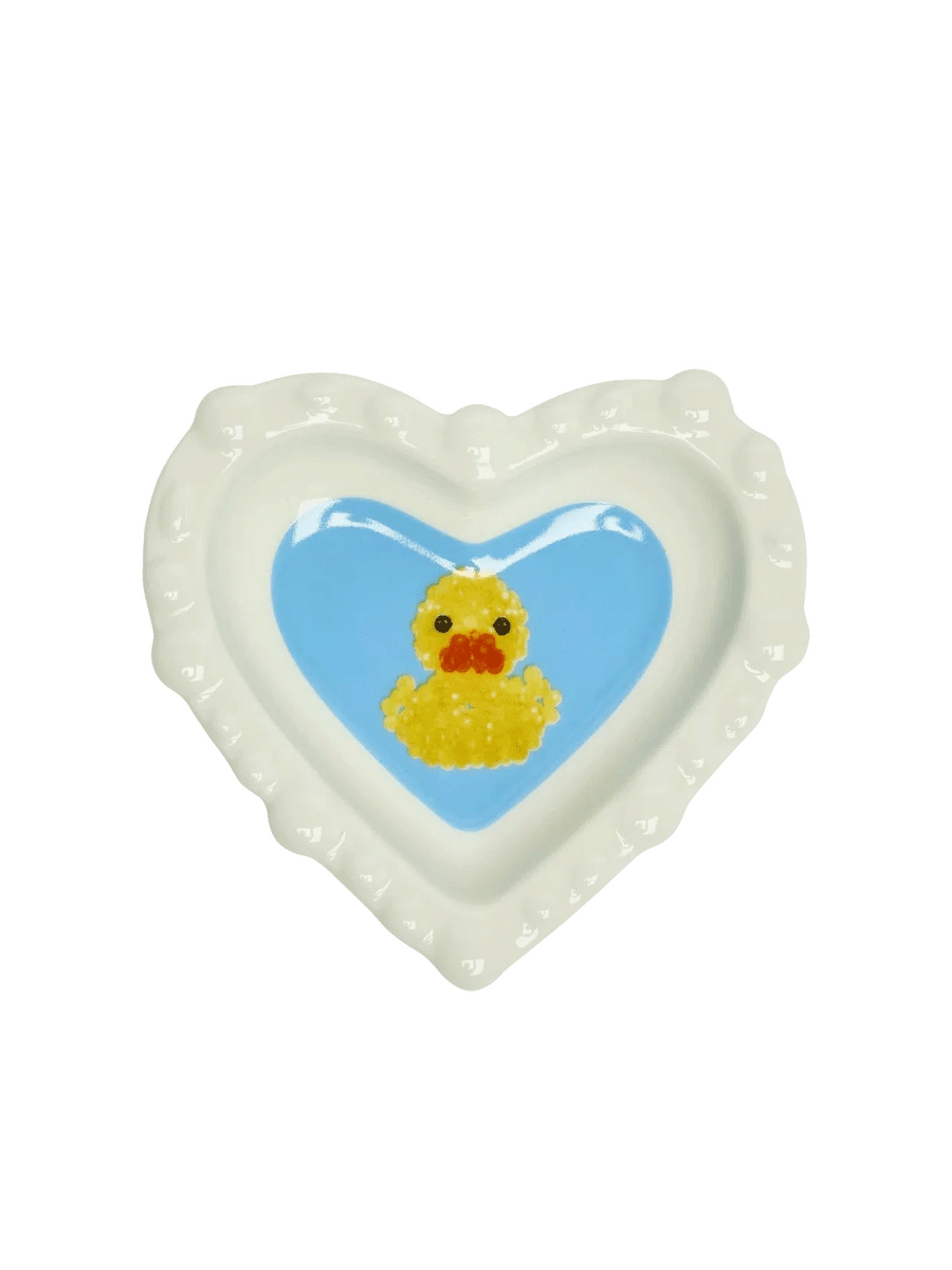 Fishs Eddy x Susan Alexandra Duckie Dish featuring a yellow duck on a blue heart-shaped centre with scalloped white edges | Twentyseven Toronto