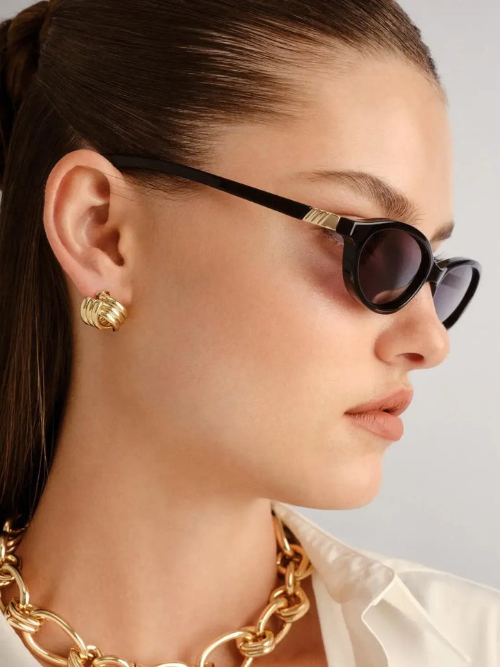 A side-profile studio view of a woman looking to the right to showcase the narrow temple arm design of the Le Specs Duskfall - Black Smoke Mono sunglasses | Twentyseven Toronto