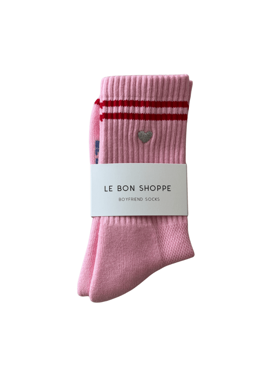 Pink 'Boyfriend Socks' with red stripes and a silver embroidered heart in 'Parchment + Heart' style with a white label featuring 'Le Bon Shoppe' branding on a transparent background | Twentyseven Toronto