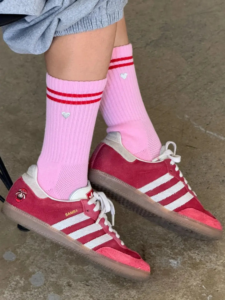 Person wearing grey sweatpants and pink 'Boyfriend Socks' with red stripes and a silver embroidered heart in 'Parchment + Heart' style from Le Bon Shoppe | Twentyseven Toronto