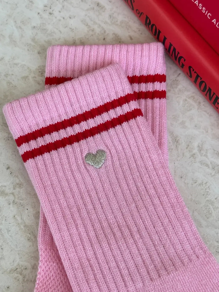 Close up of pink 'Boyfriend Socks' with red stripes and a silver embroidered heart in 'Parchment + Heart' style from Le Bon Shoppe on a neutral background | Twentyseven Toronto