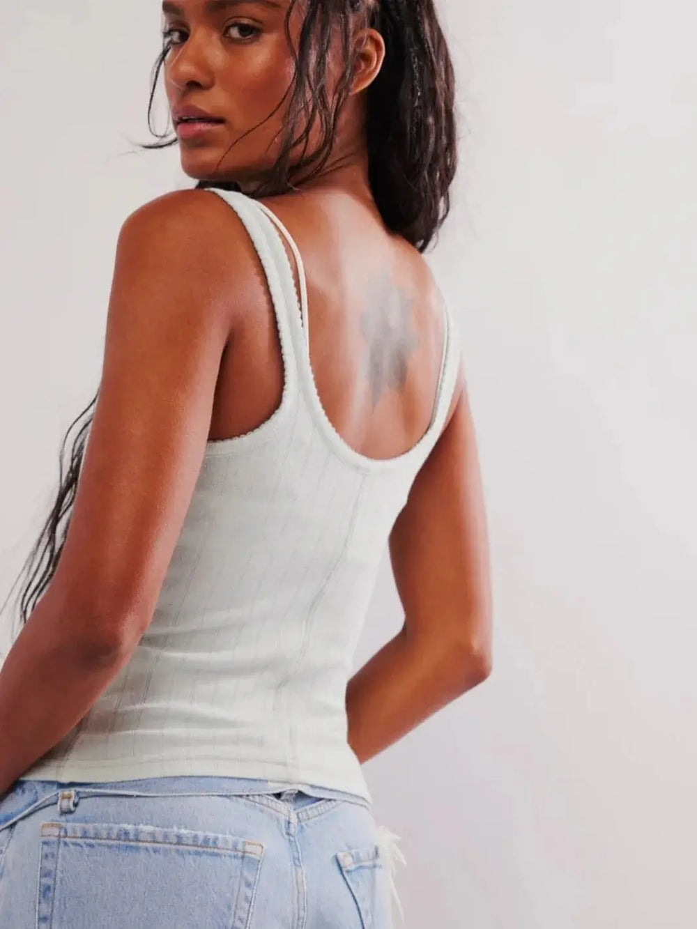  A three-quarter view from behind showcases the classic scoop neckline, slim-fitting ribbed design, and shoulder strap details of the light blue Free People End Game Pointelle Tank - Pale Aqua | Twentyseven Toronto
