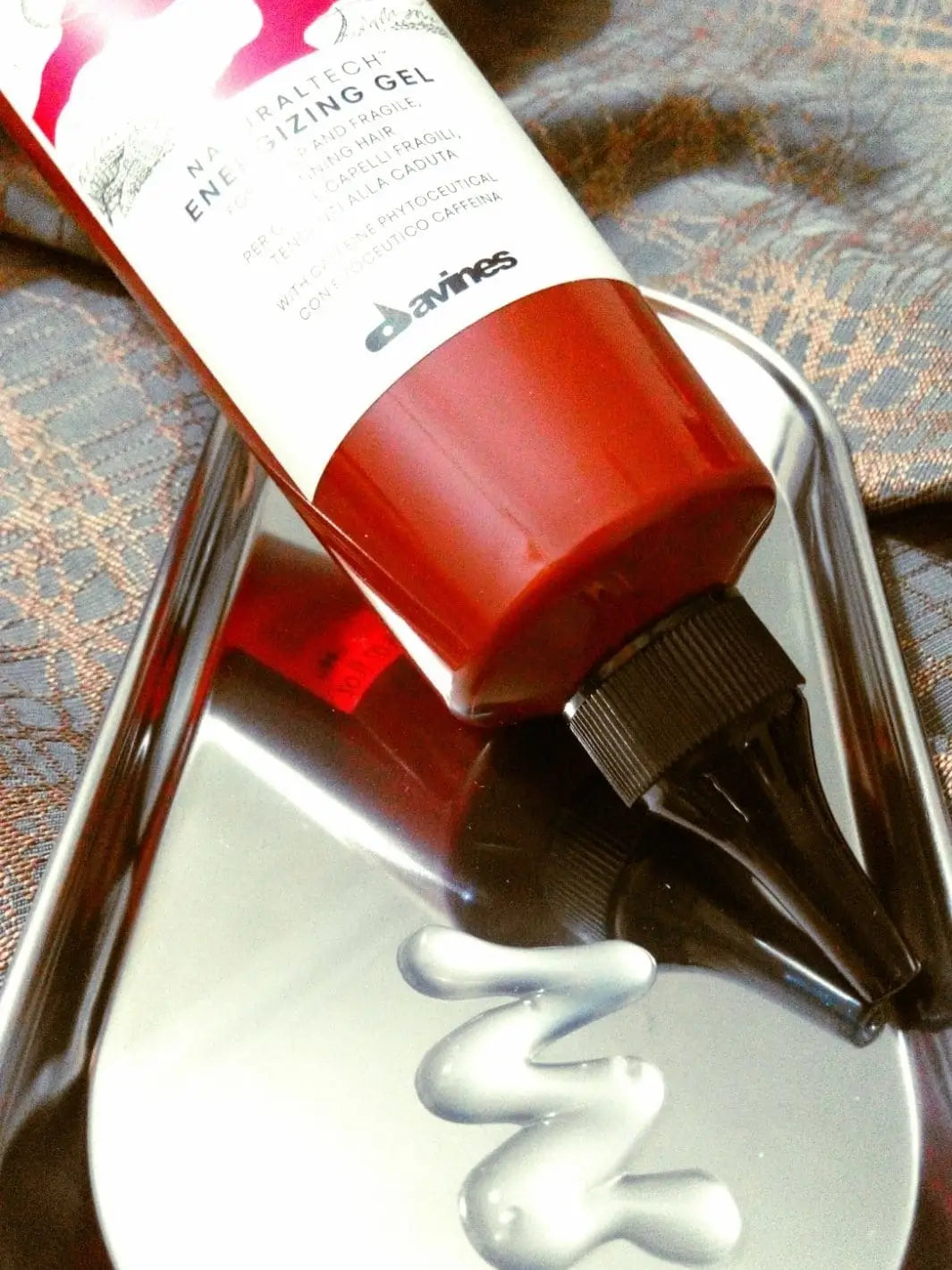 A tube of Davines ENERGIZING Gel rests on a reflective silver tray next to a dollop of clear product | Twentyseven Toronto